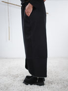 Seitliche Ansicht der schwarzen weiten Hose mit Zipper-Details am Beinabschluss